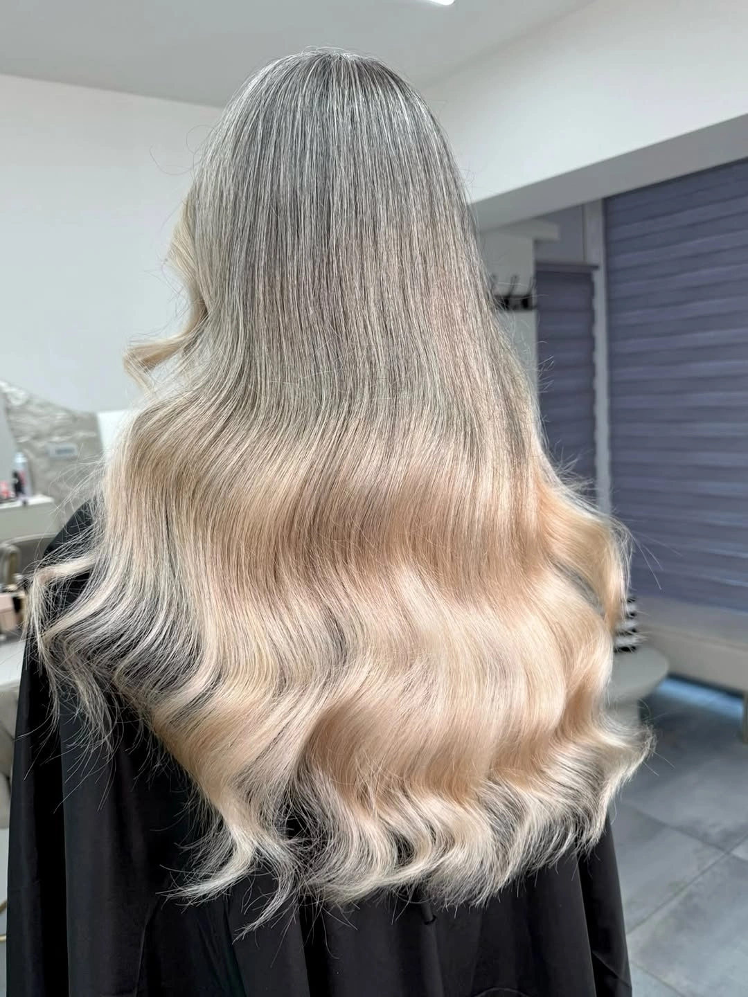 Back view of long blonde hair with smoky darker roots