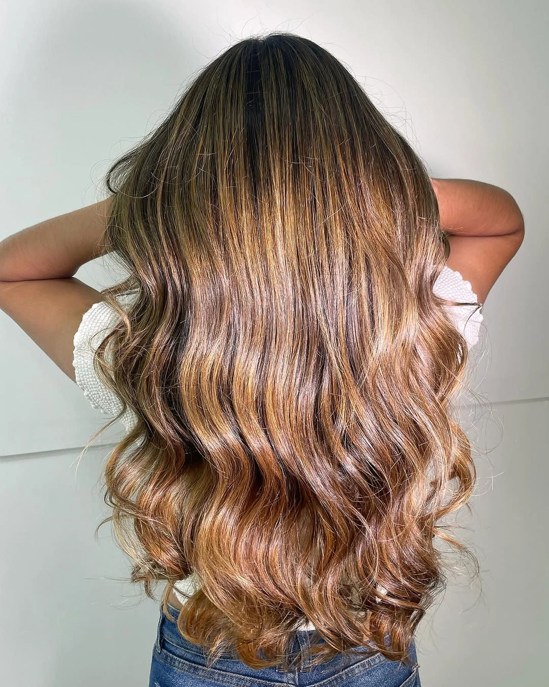 Long brunette waves with honey-caramel ribbons and darker roots