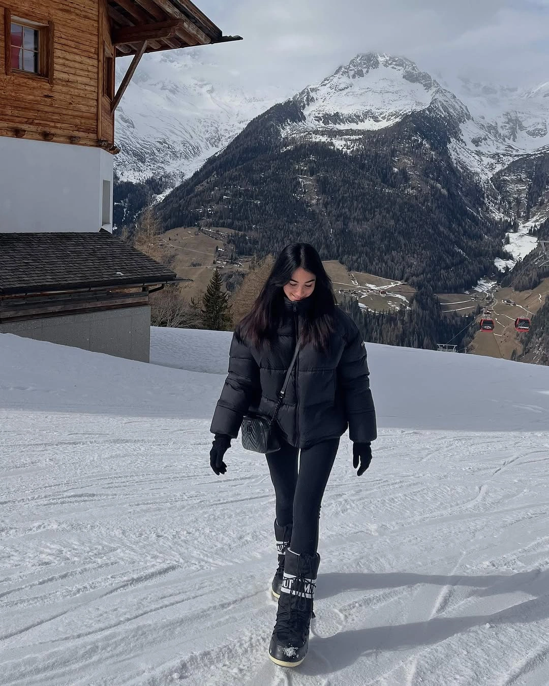 Woman in black puffer jacket leggings gloves and winter boots