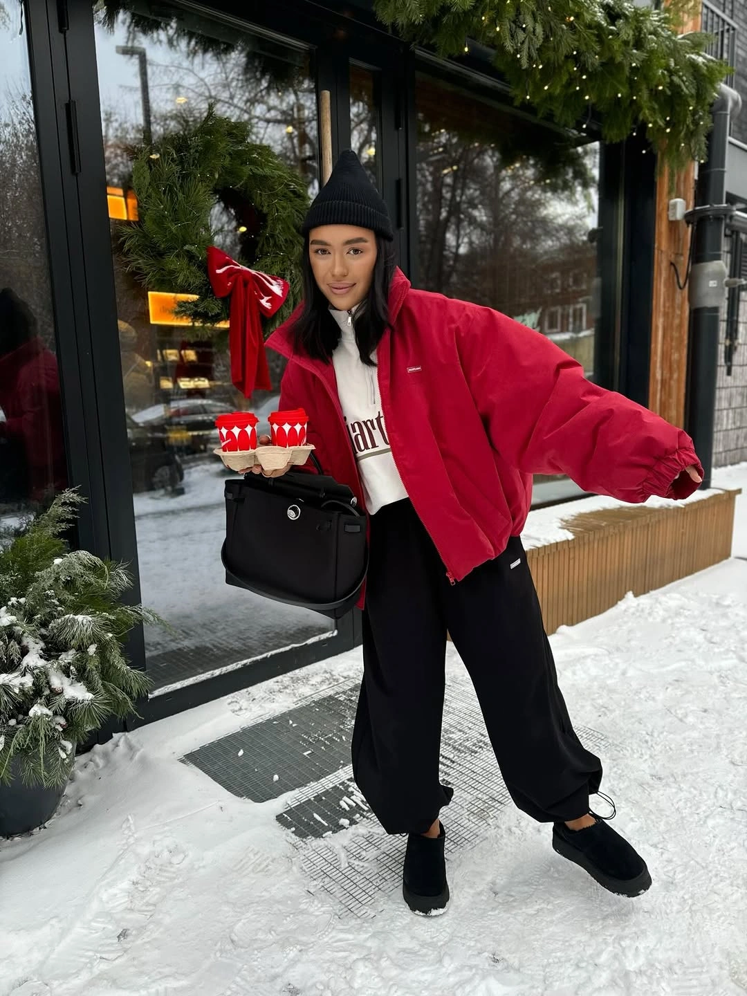Woman in red jacket black beanie white top and jogger pants