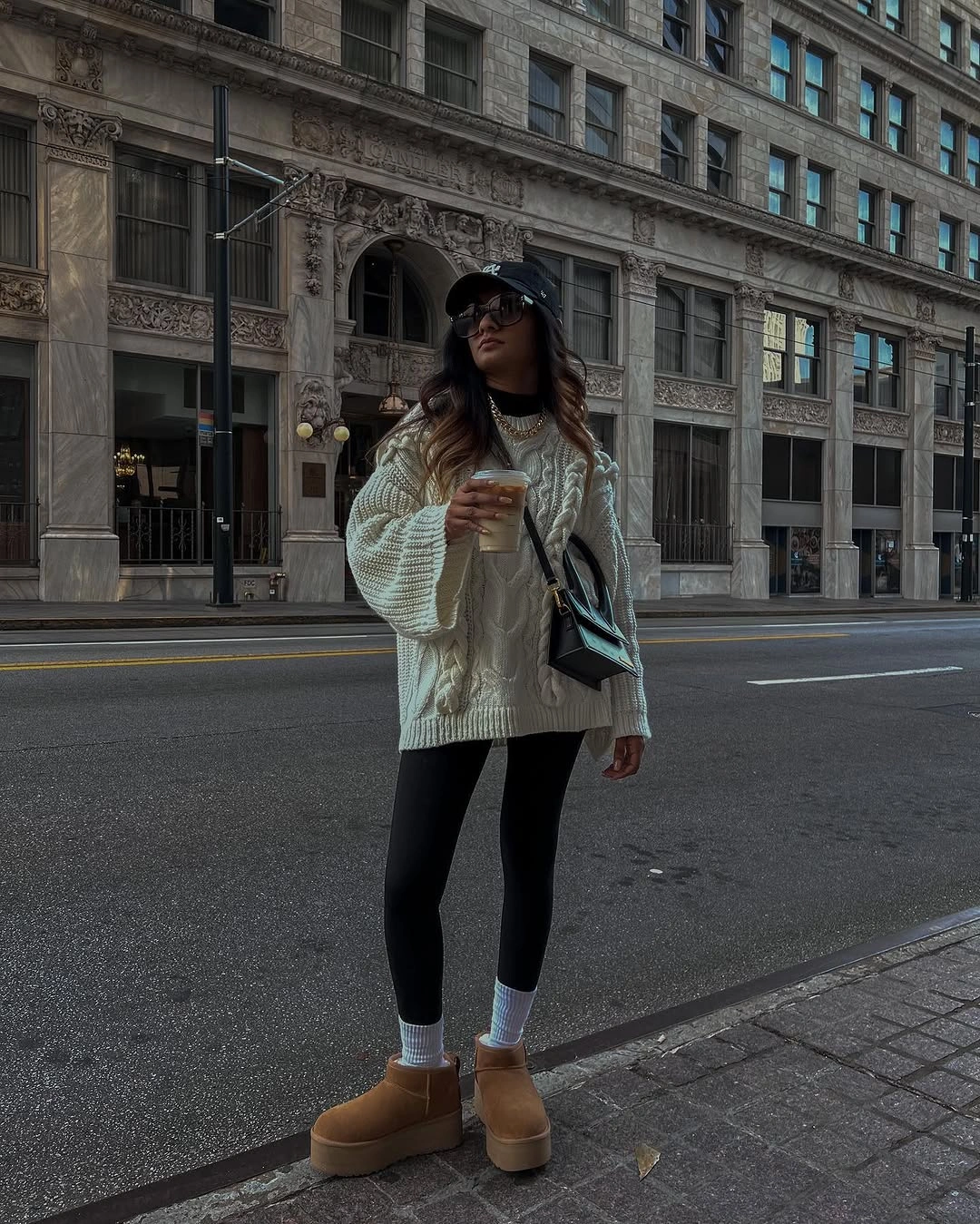 Woman in oversized textured sweater black leggings and tan boots