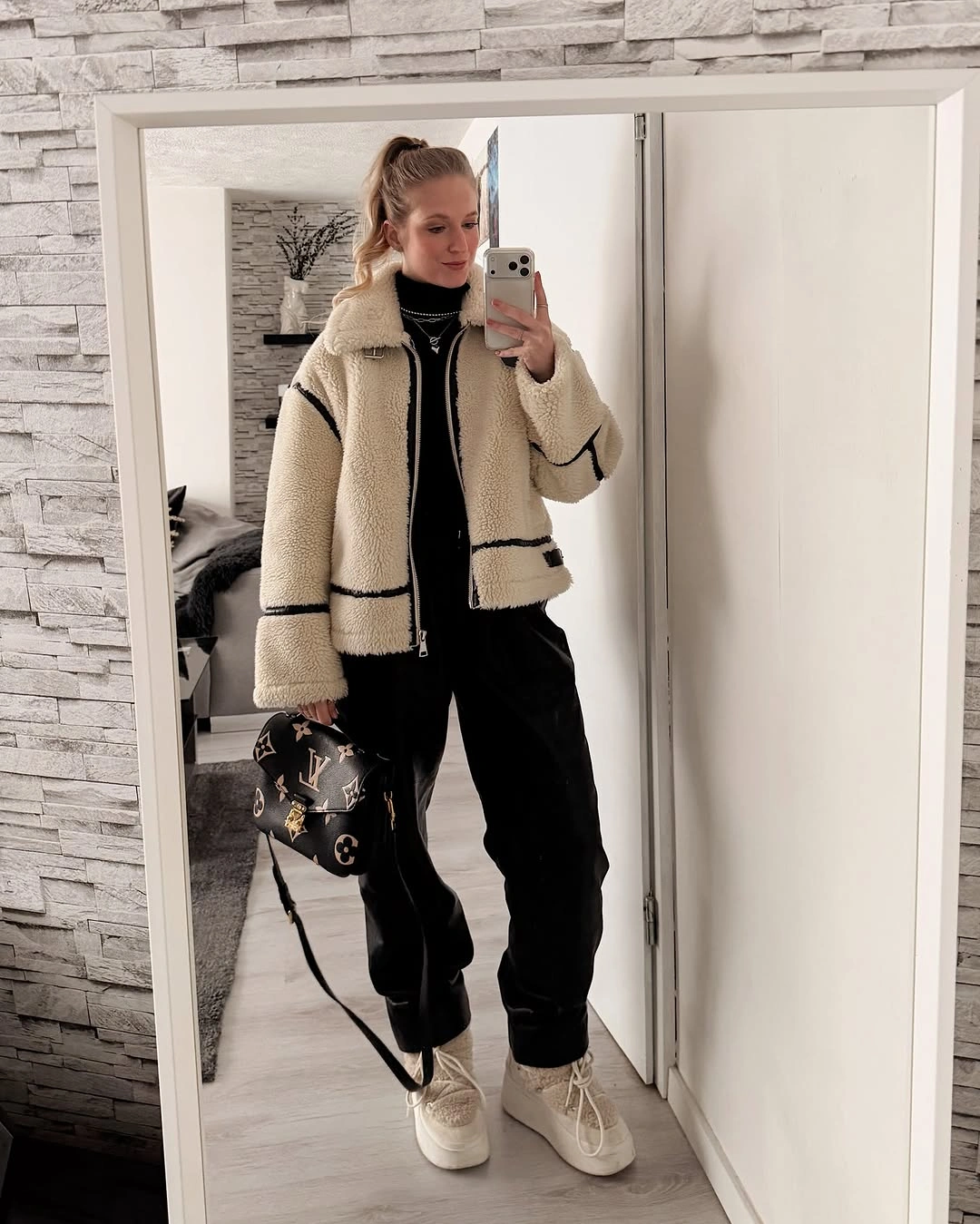 Woman in cream sherpa jacket black joggers and white sneakers