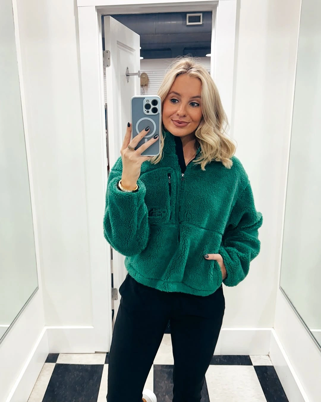Woman in emerald fleece jacket black pants and white sneakers