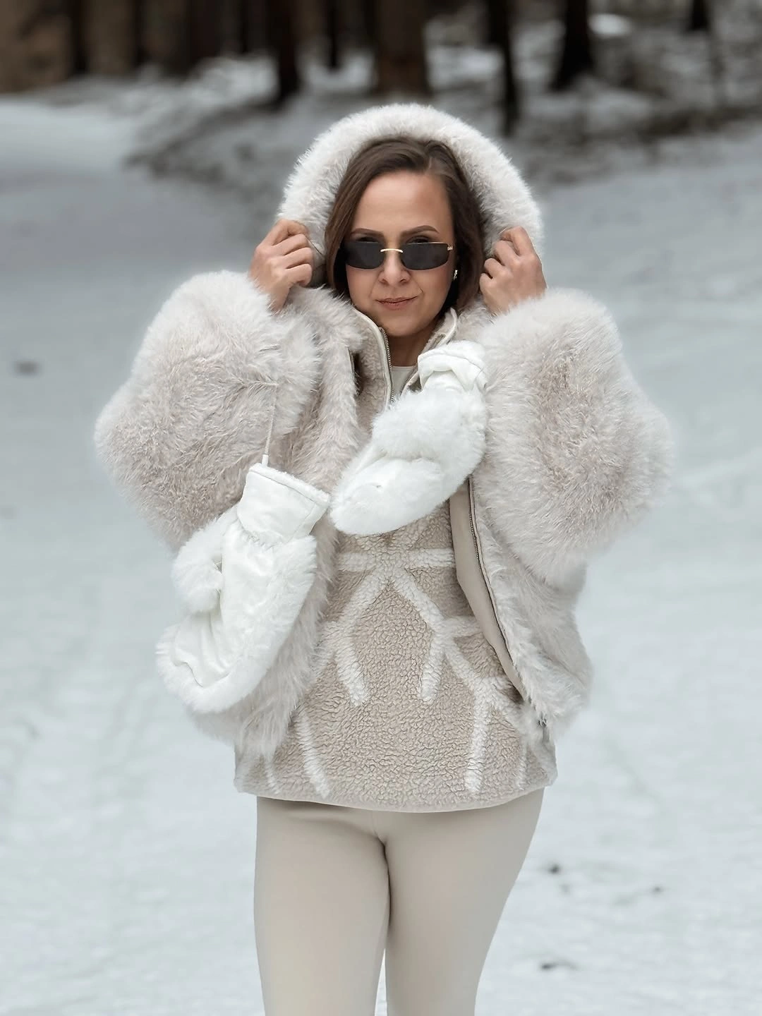 Woman in cream textured coat white hoodie and light pants
