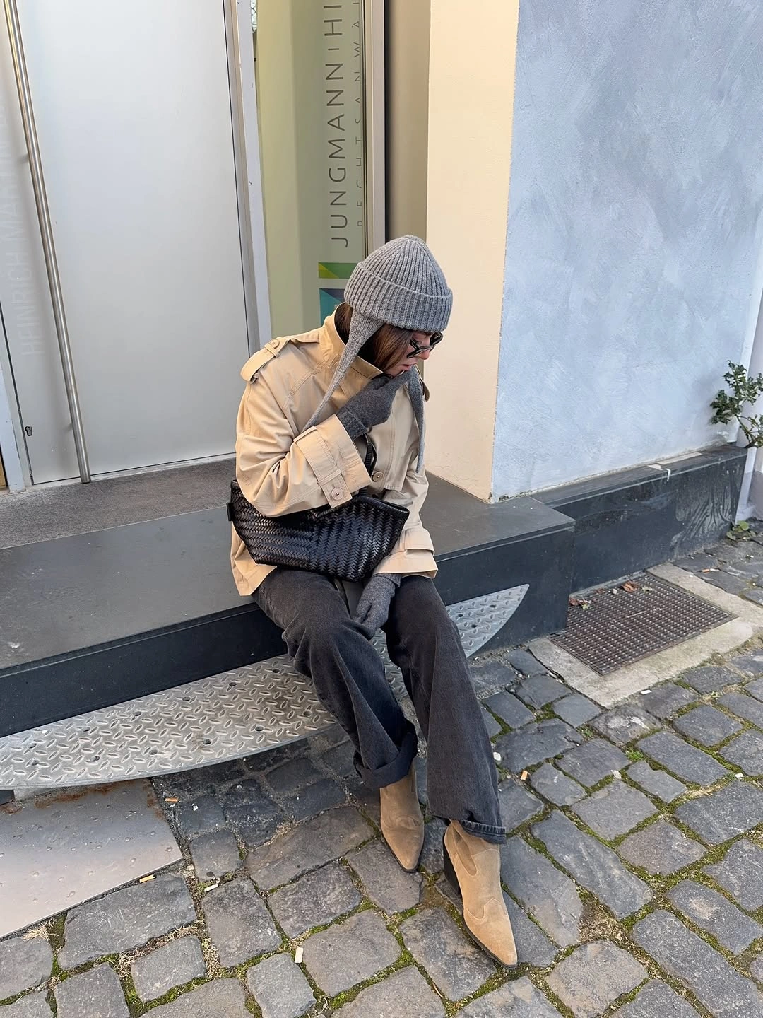 Beige jacket with gray beanie, charcoal jeans, tan boots, and dark bag