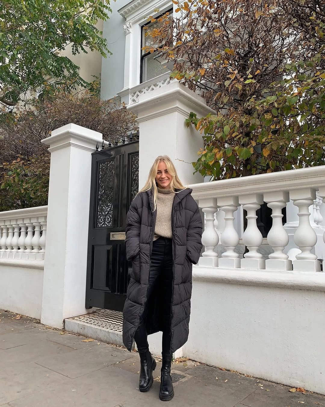 Long black puffer with cream high-neck knit, dark trousers, and ankle boots