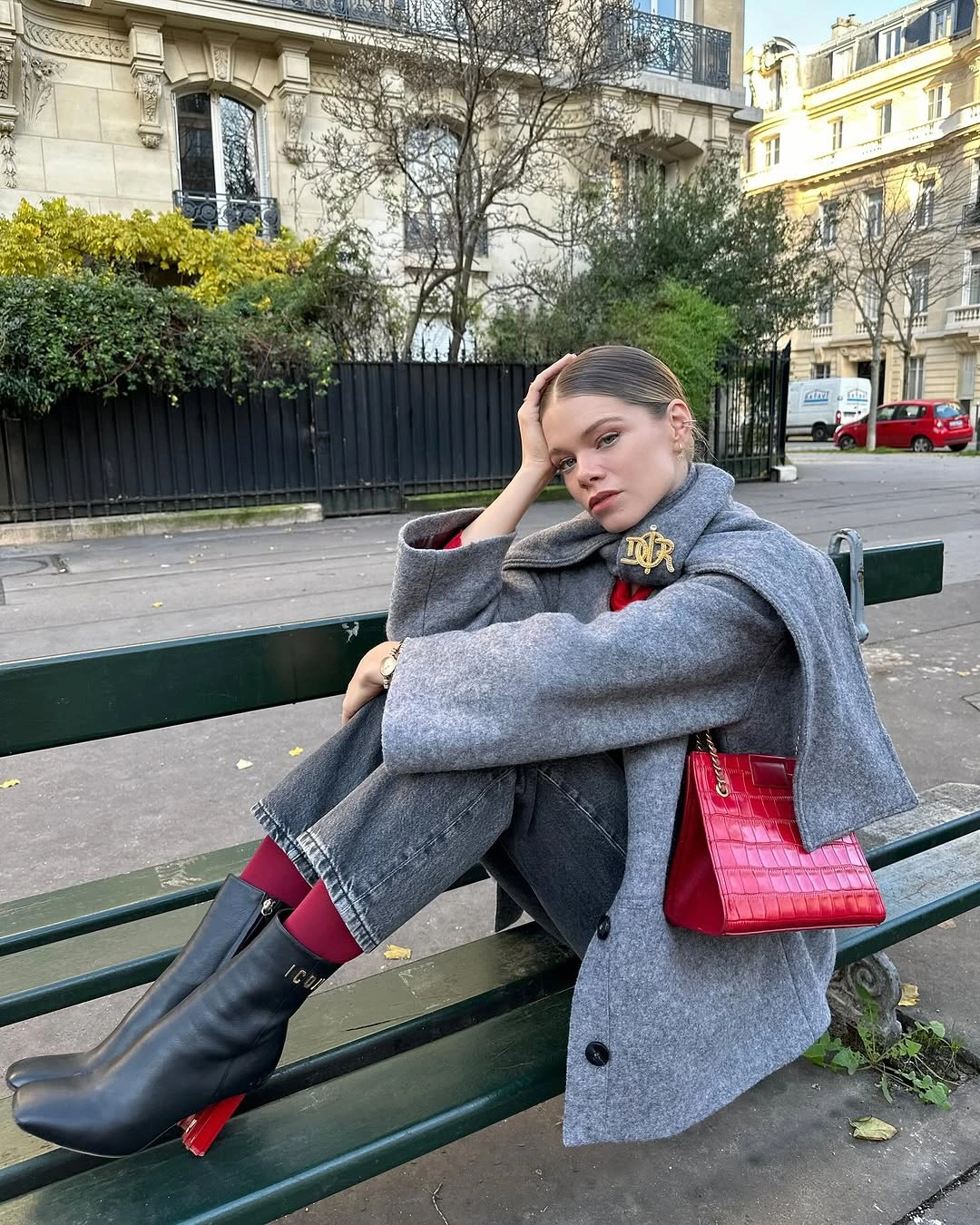 Oversized gray coat and jeans with red bag, red socks, and black boots