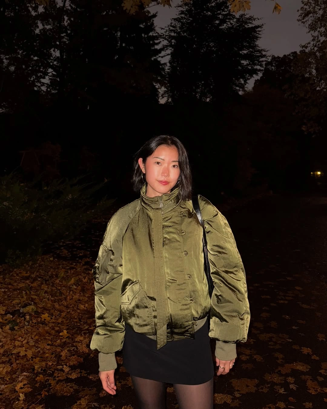Olive bomber jacket with black mini skirt and sheer black tights