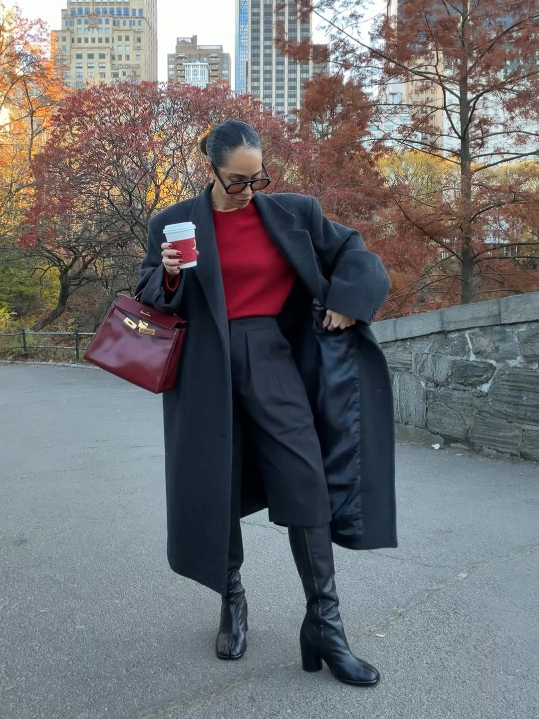 Long dark coat with red top, wide trousers, and deep red handbag