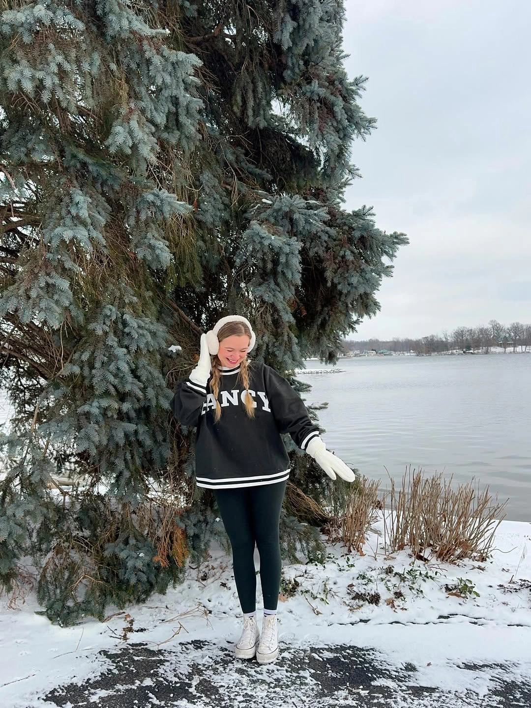 Black sweatshirt and leggings with white earmuffs, gloves, and lace-up shoes