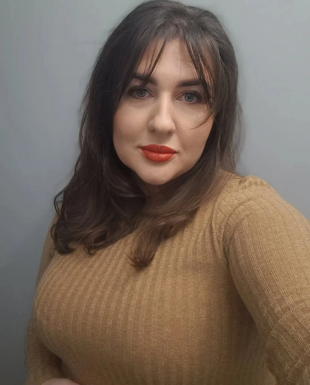 Dark shoulder-length hair with wispy bangs and curled-under ends
