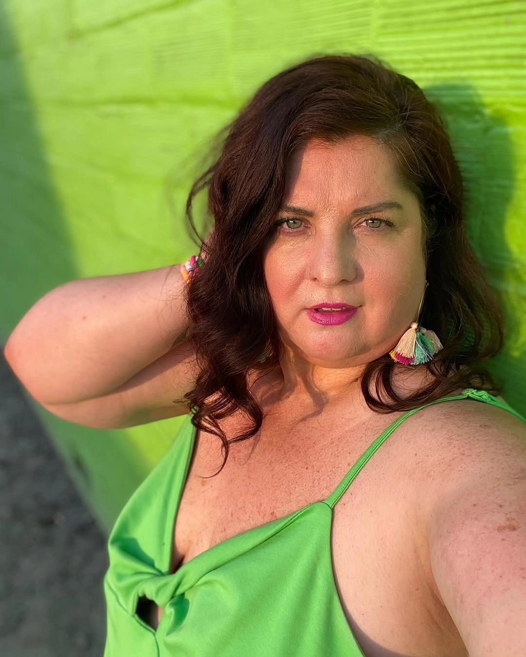 Shoulder-length auburn waves with green top and tassel earrings