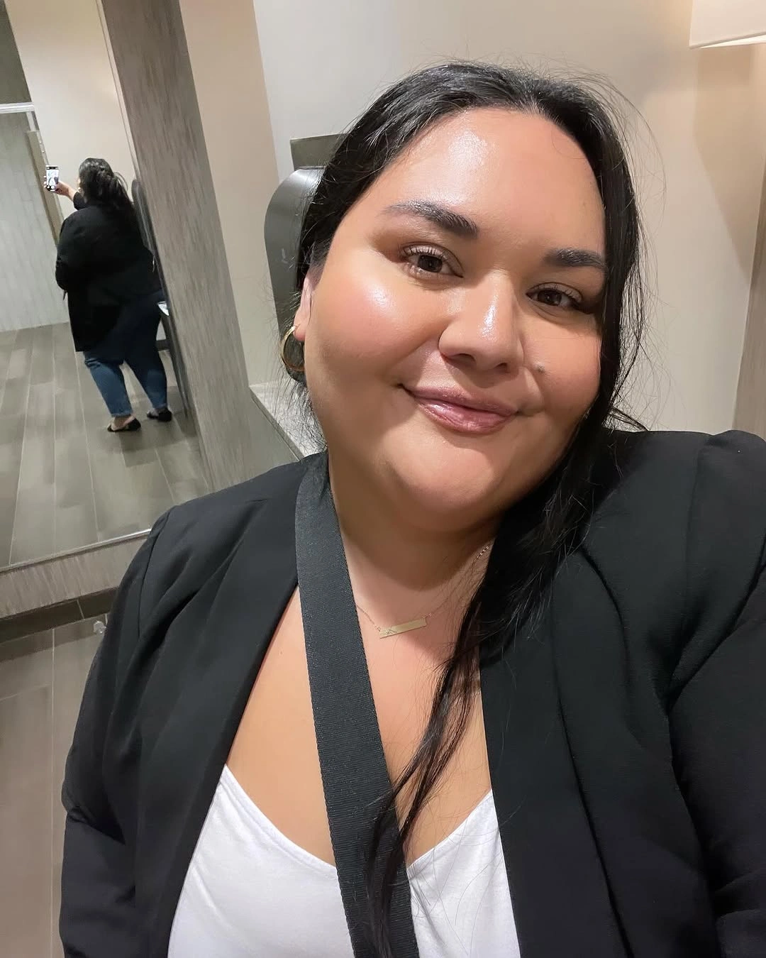 Long dark hair over one shoulder with black blazer and white top
