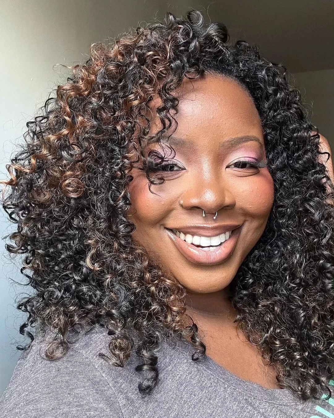 Shoulder-length tight curls with caramel-highlighted pieces
