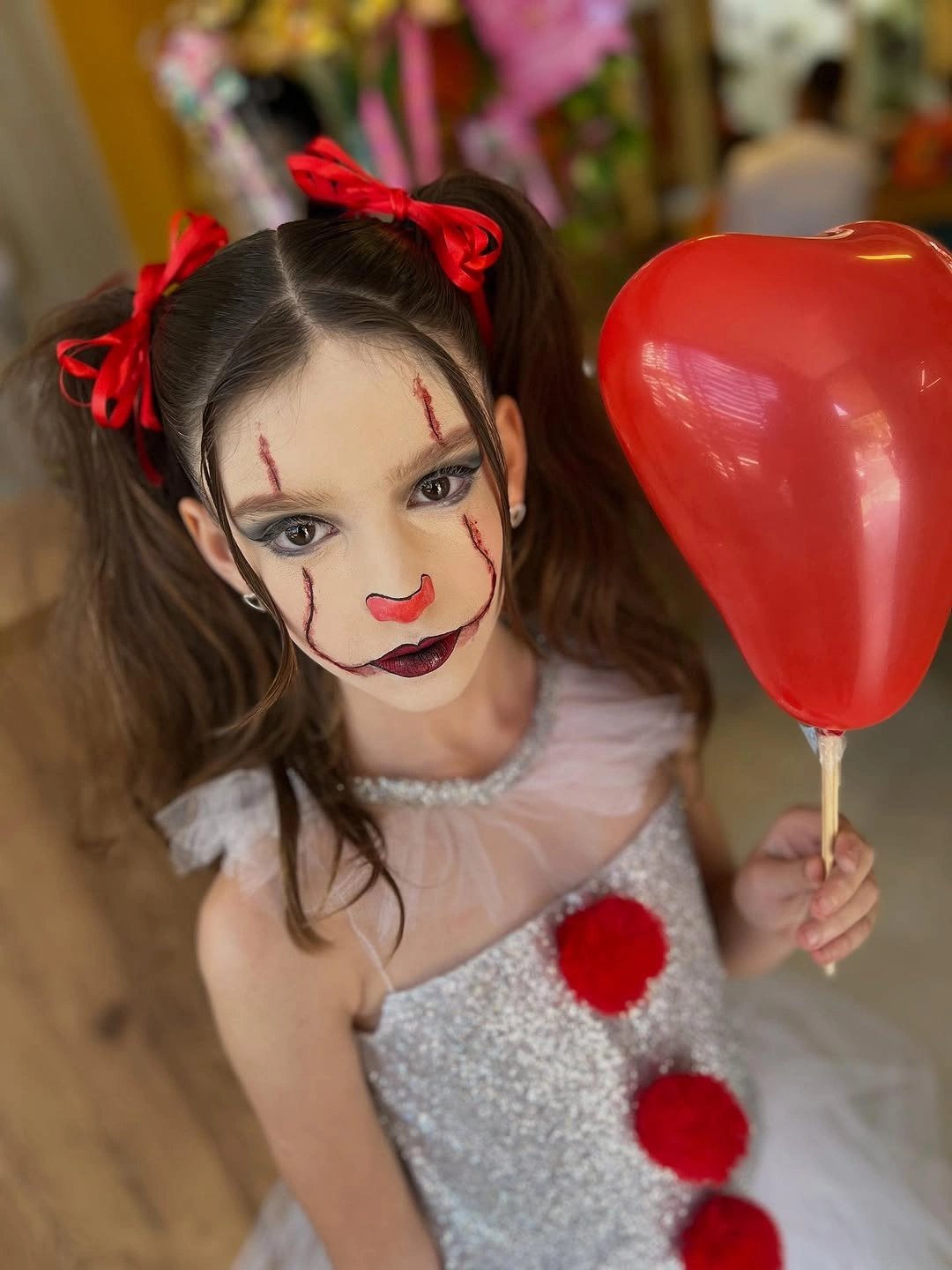 Pale doll costume with red hair bows and dramatic face paint