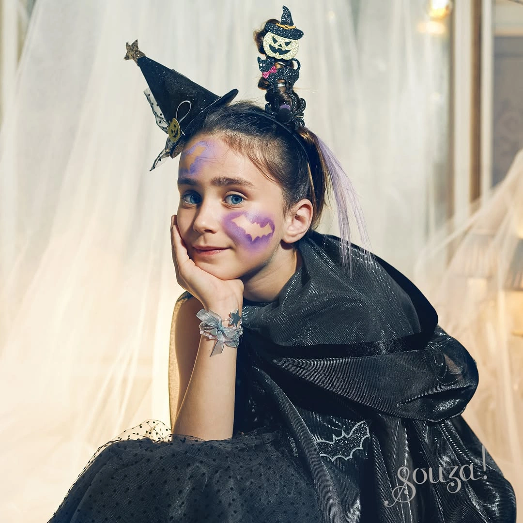 Playful black witch costume with purple face paint and hat