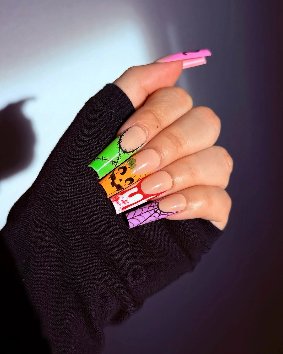 Long clear Halloween nails with neon orange stitches and pumpkins