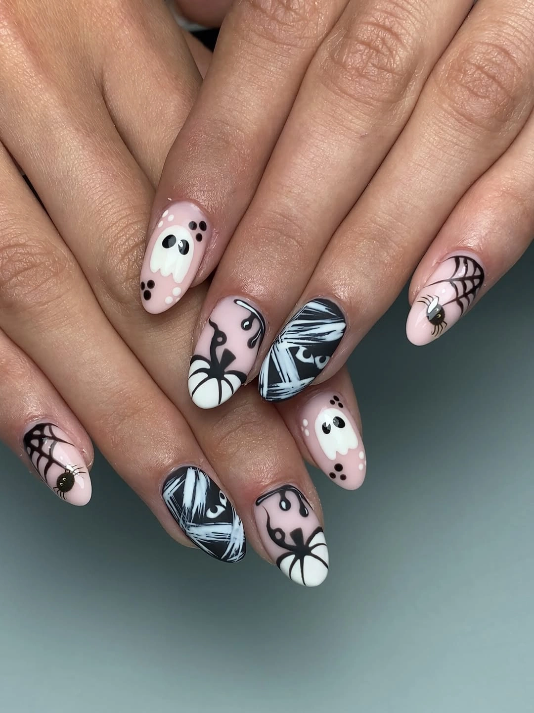 Pale pink almond Halloween nails with ghosts pumpkins and webs