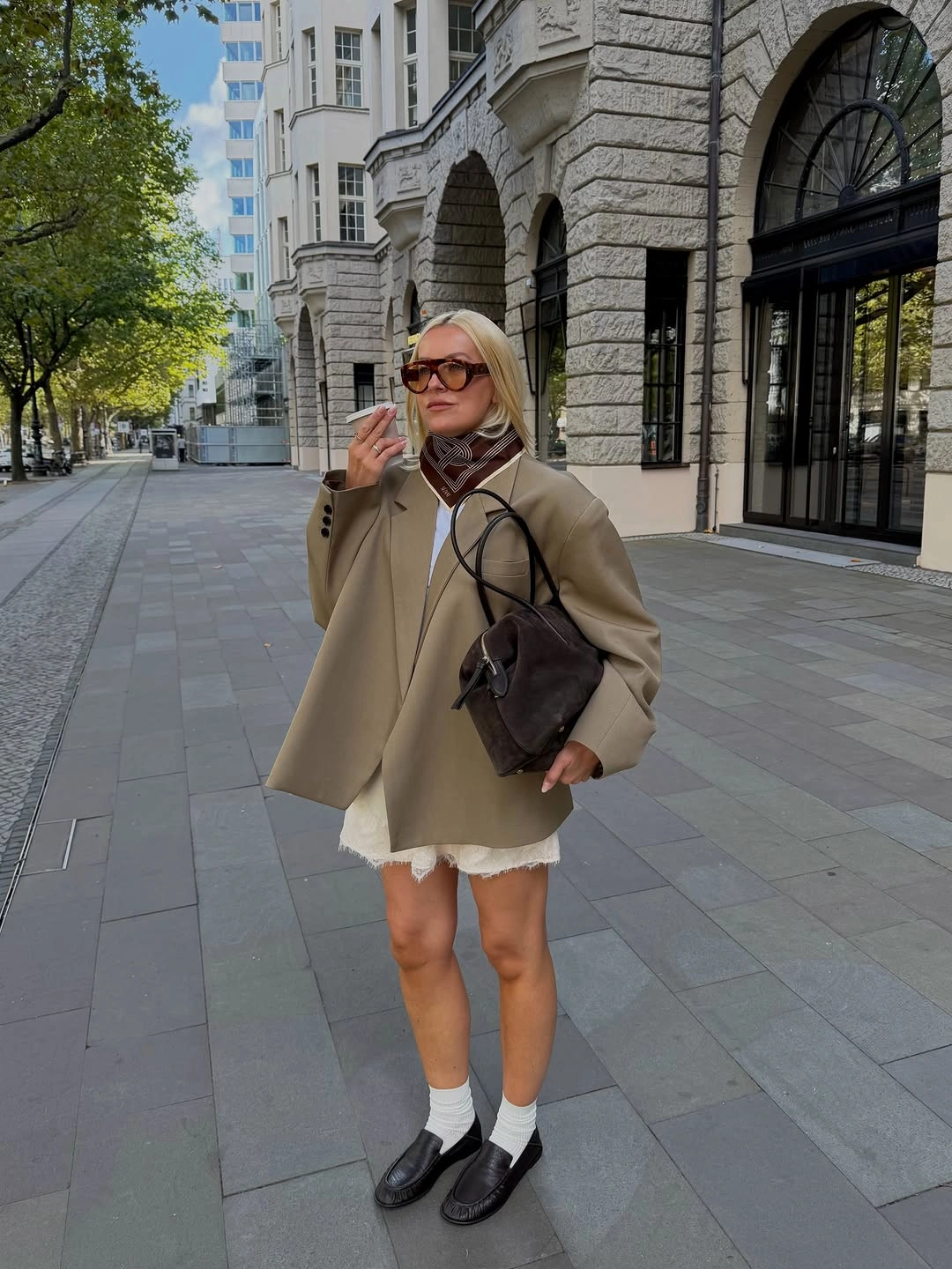 Beige swing coat with lace hem, loafers and brown bag