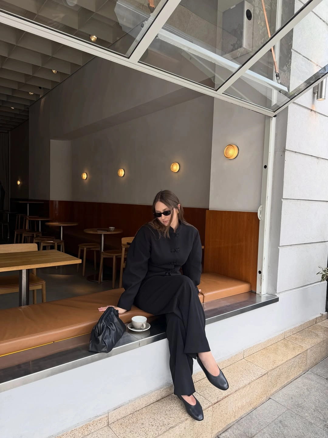All-black seated outfit with flats and dark bag
