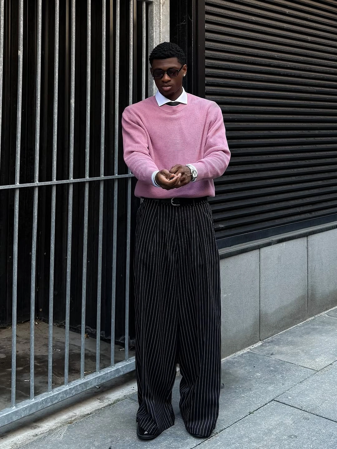 Pink sweater white collar black pinstripe wide trousers and dark shoes