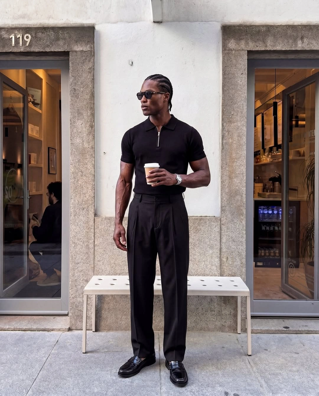 Black zip polo with wide black trousers sunglasses and dark shoes