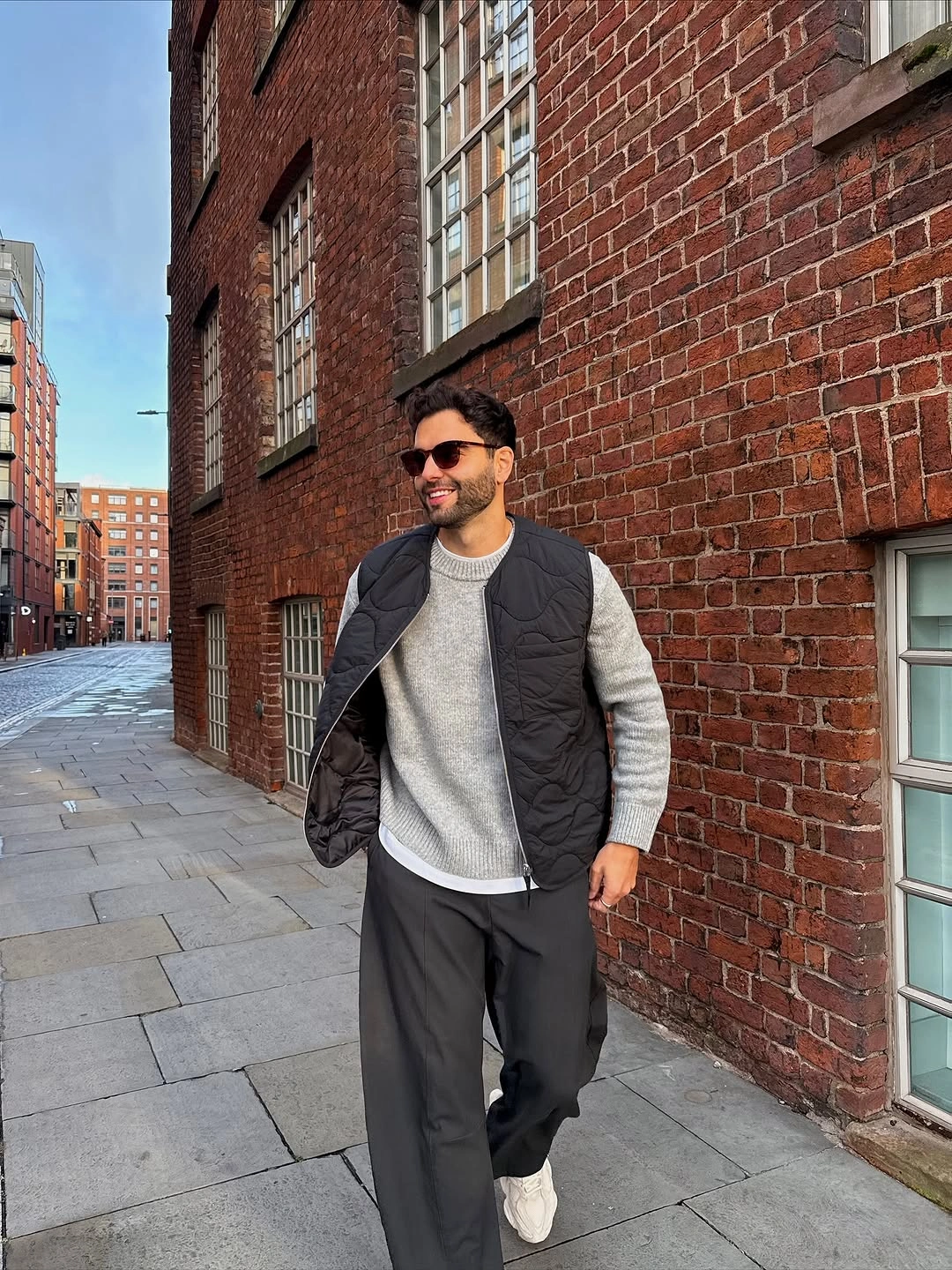 Black quilted vest gray sweatshirt charcoal wide trousers and sunglasses