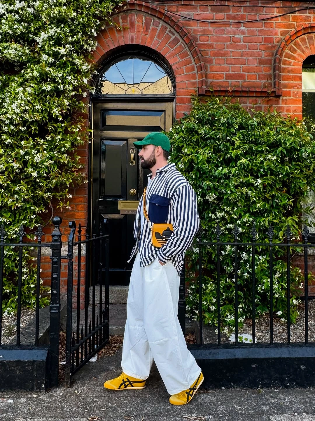 Blue striped overshirt white wide trousers green cap yellow shoes crossbody bag
