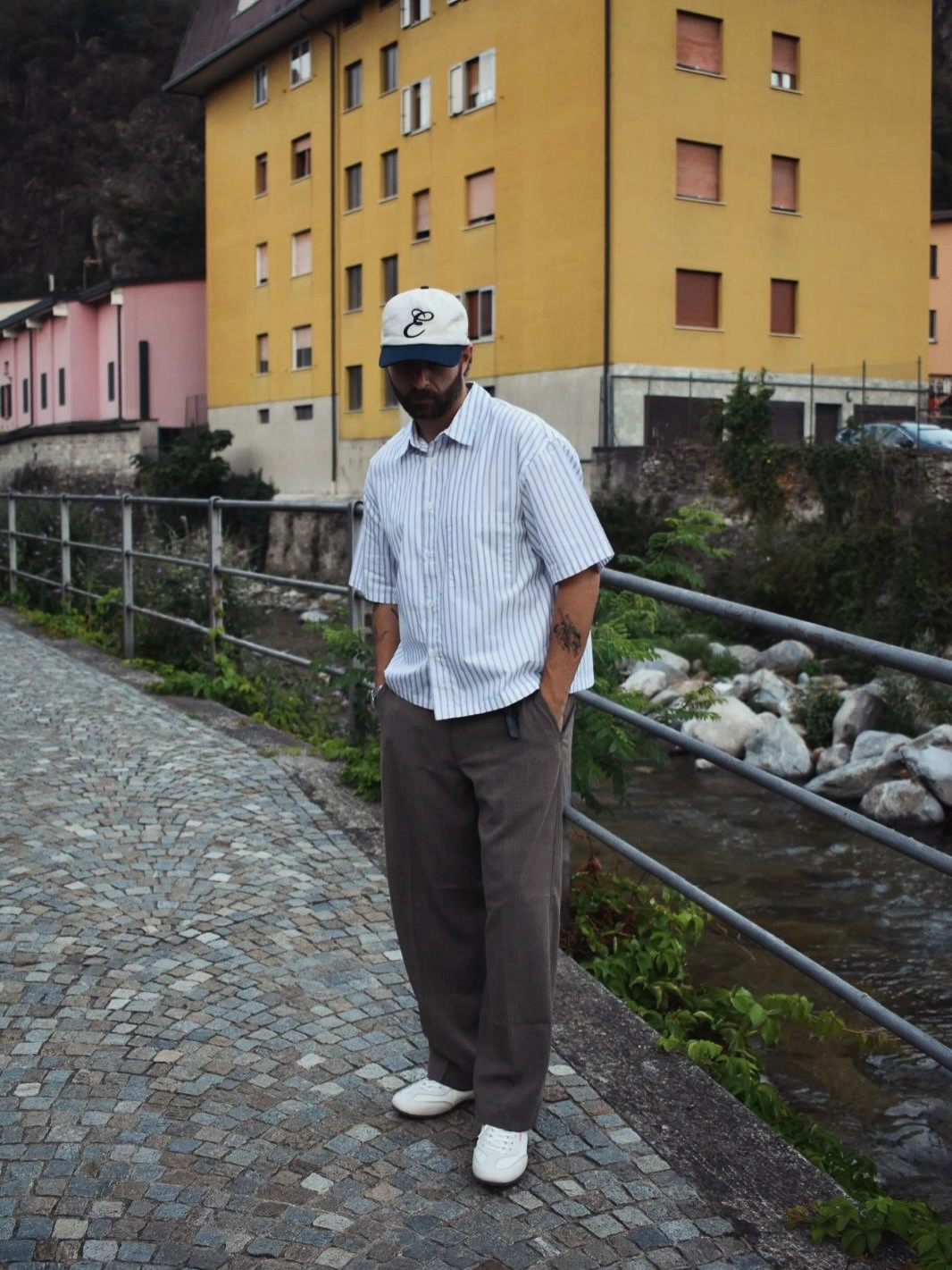 Light blue striped short sleeve shirt dark loose trousers cap and white sneakers