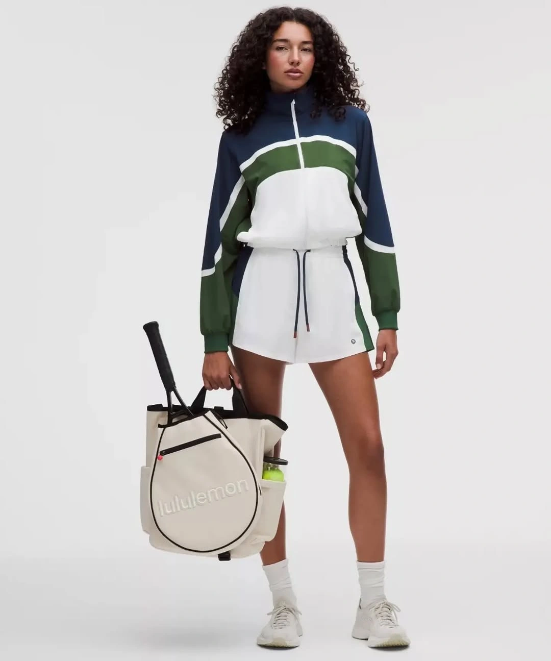 White zip athletic top green navy panels white skirt and padel racket bag