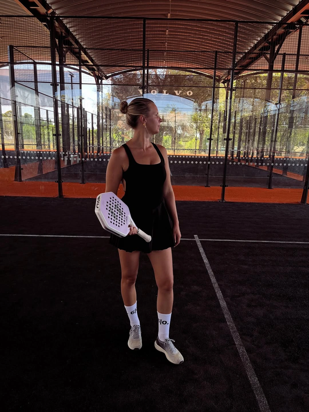 Black sleeveless athletic dress long white socks shoes and white padel racket