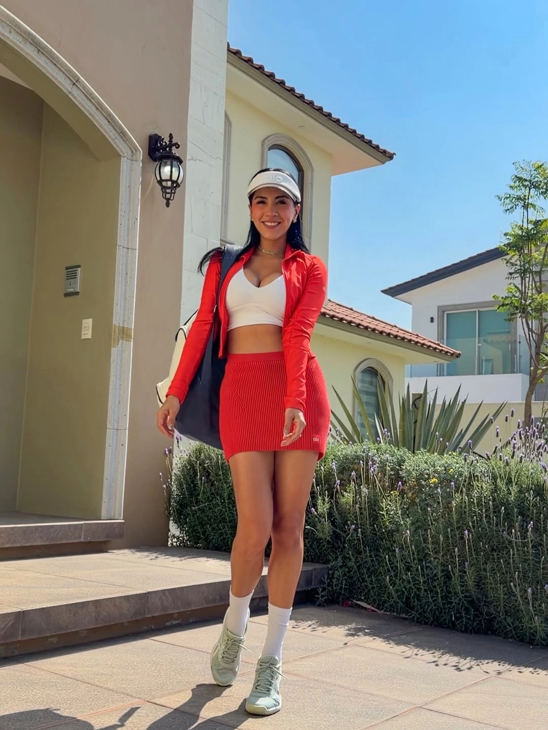 Red cardigan white sports top red skirt white cap shoes and padel racket