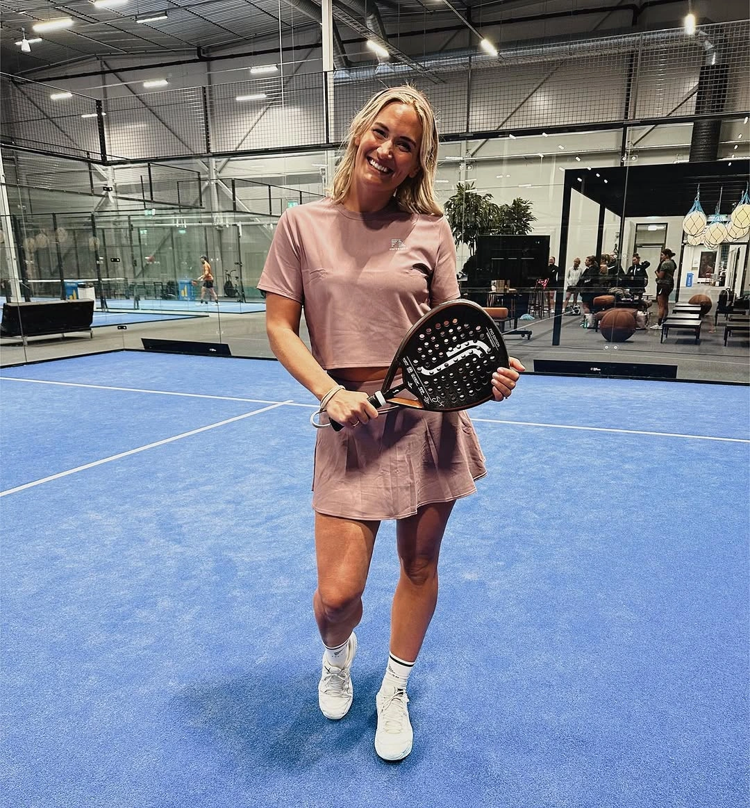 Dusty pink short sleeve athletic dress white socks shoes and black padel racket