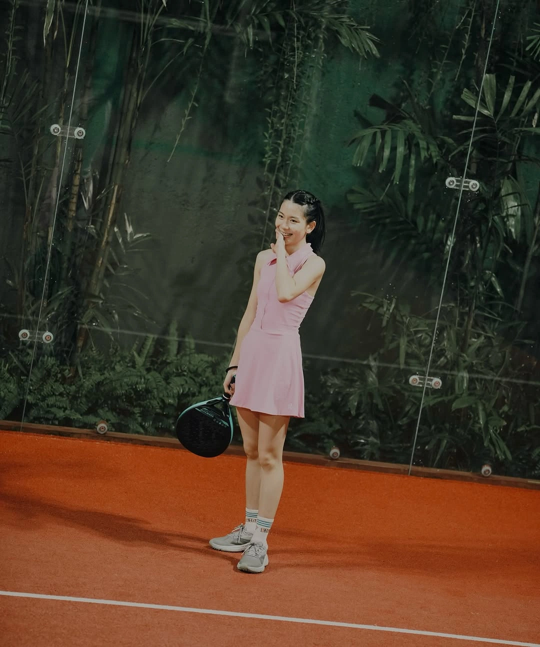 Light pink sleeveless athletic dress white cap socks shoes and padel racket