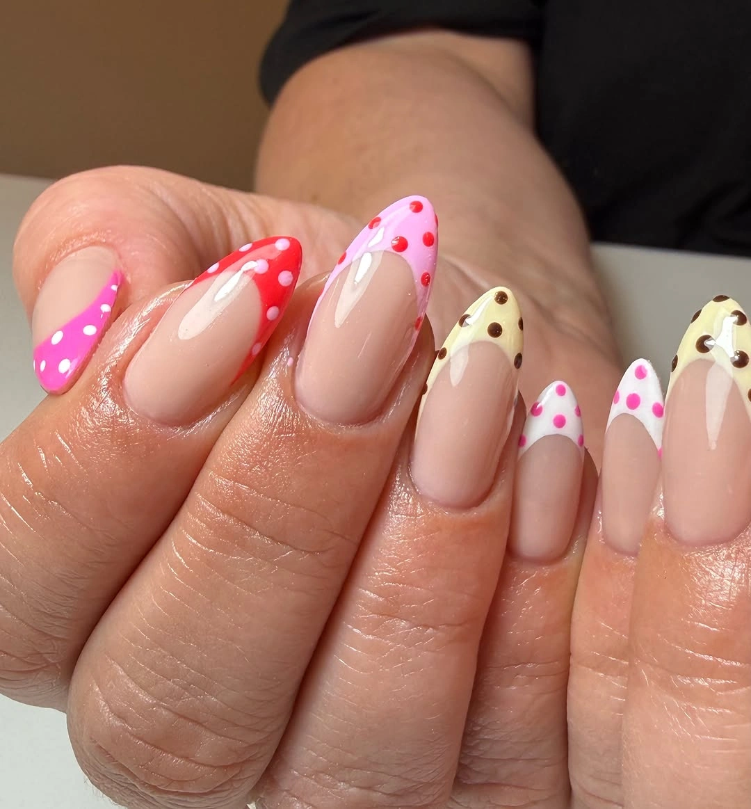 Almond nude nails with red pink yellow tips and white dots