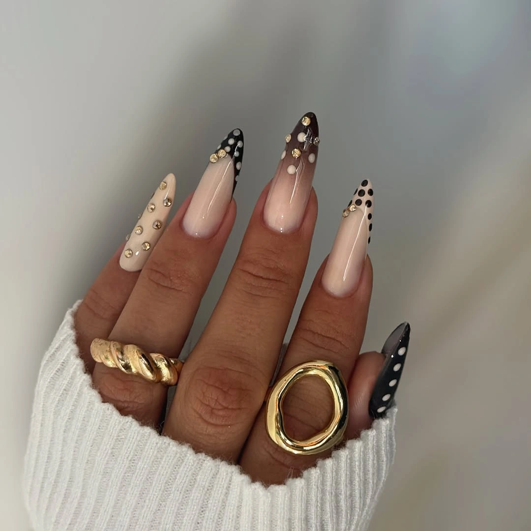 Long almond nude nails with black accents white dots and pale details