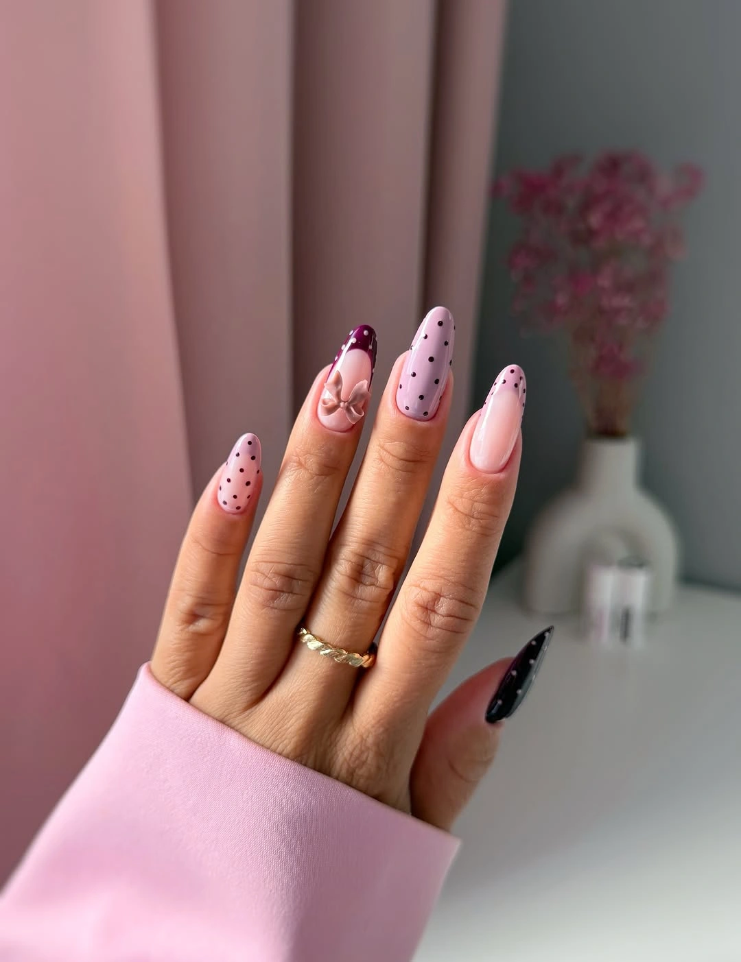 Long pink stiletto nails with black dots and burgundy accents