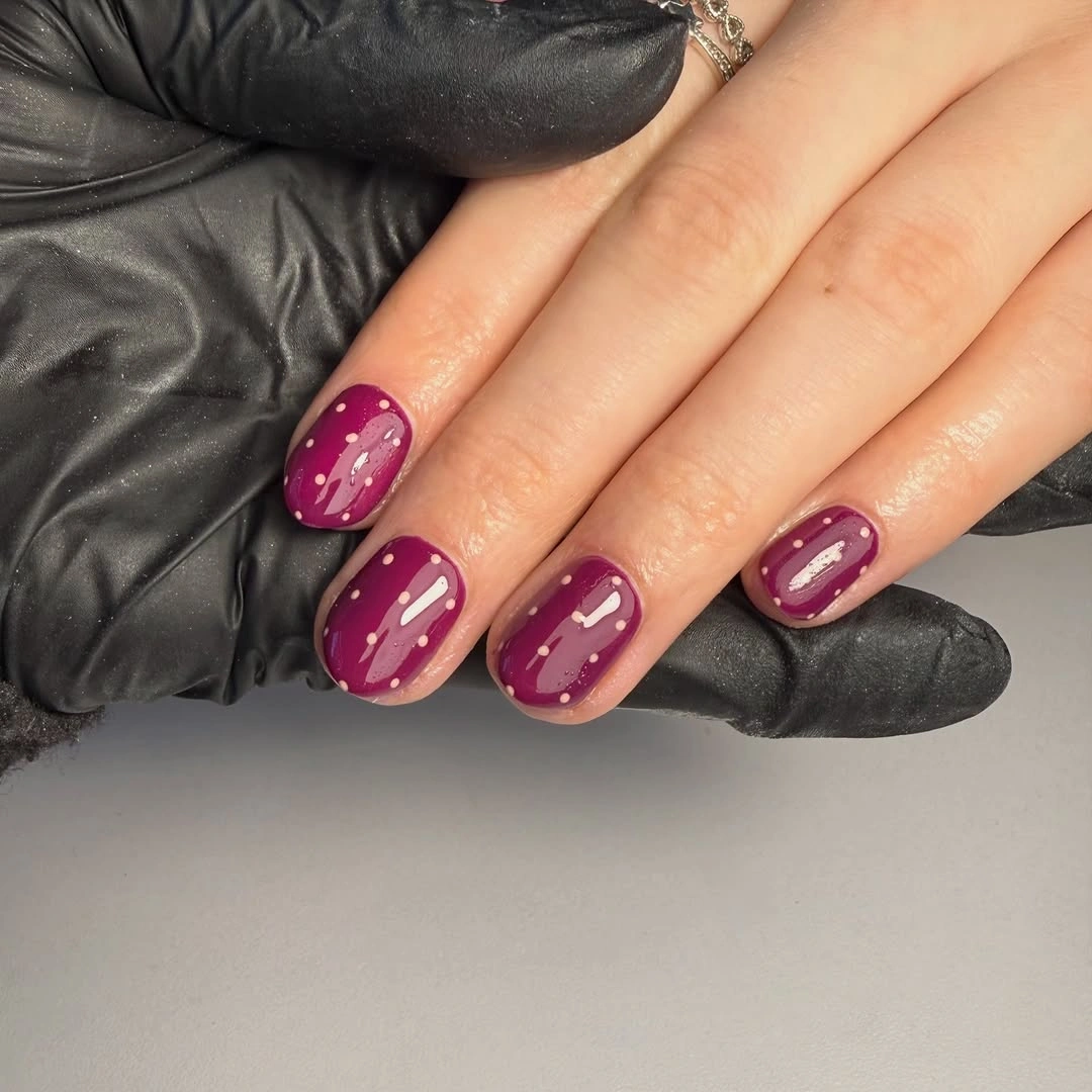 Glossy berry almond nails with pale curves and white dot accents