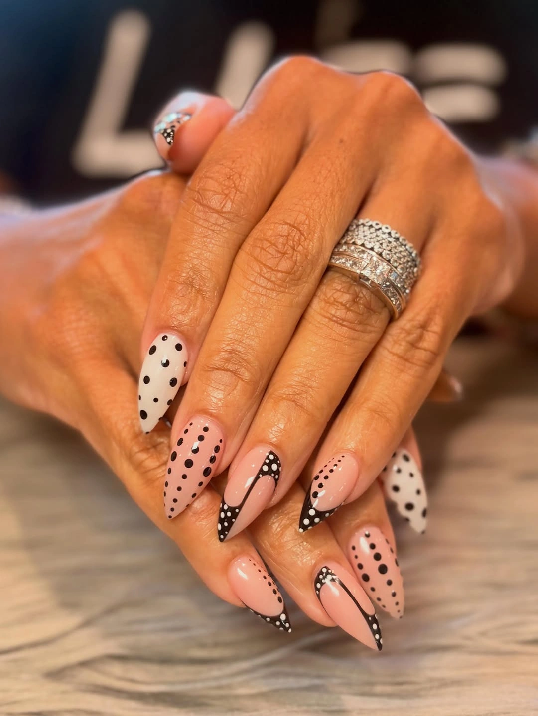 Long nude stiletto nails with black and white polka dot accents