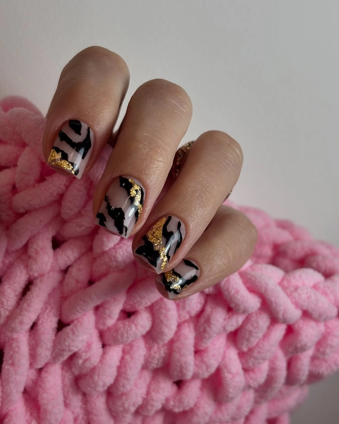 Short rounded-square nails with black and white abstract art and gold streaks