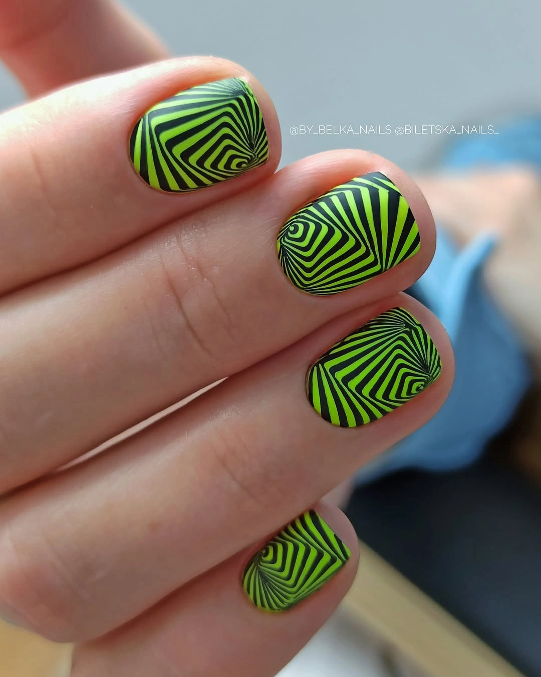 Short rounded nails with neon green and black optical lines