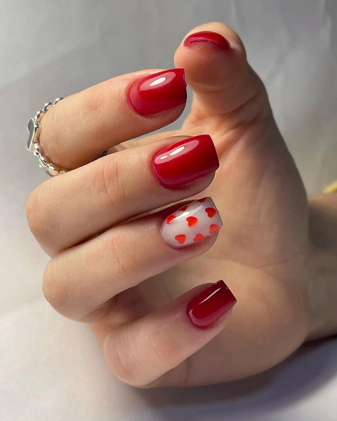 Short-to-medium square red nails with pale heart accent