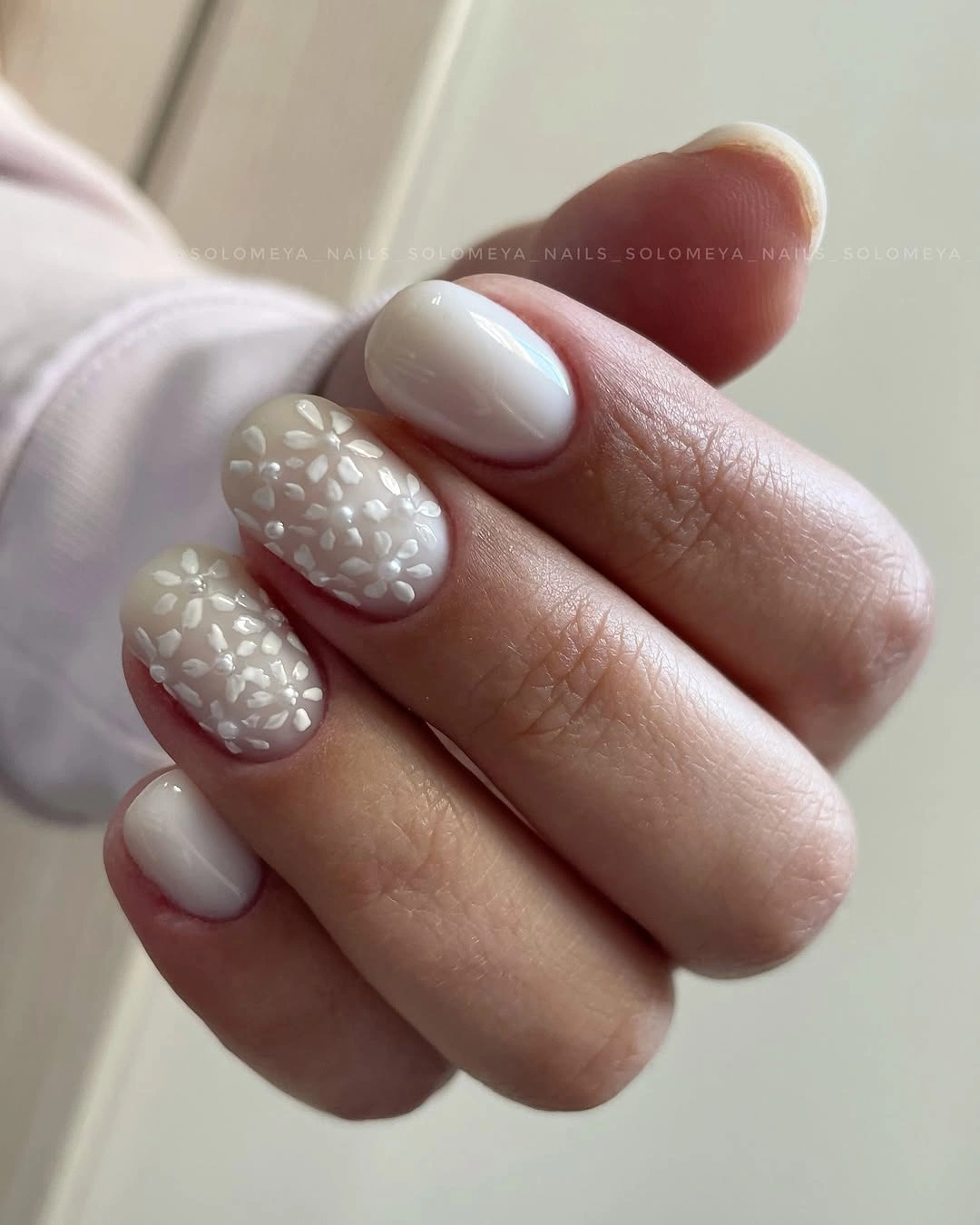 Milky white short oval nails with raised floral clusters