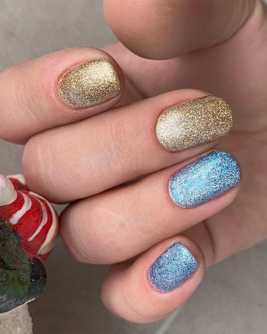 Short rounded nails with gold and blue full glitter polish