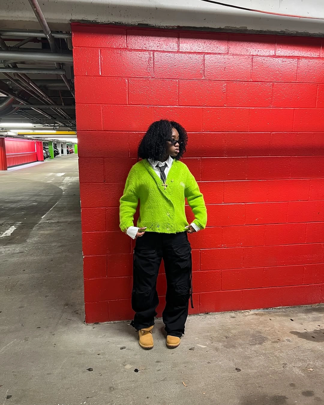 Lime green hoodie with black wide trousers and tan boots