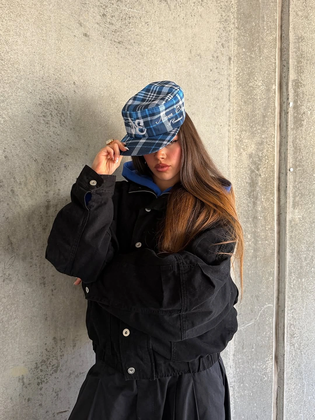 Black utility jacket with blue plaid cap and dark lower layer