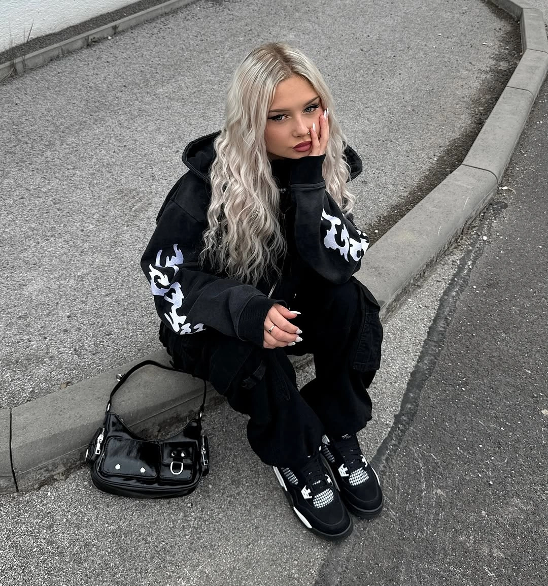 Black graphic hoodie with loose dark pants and two-tone sneakers