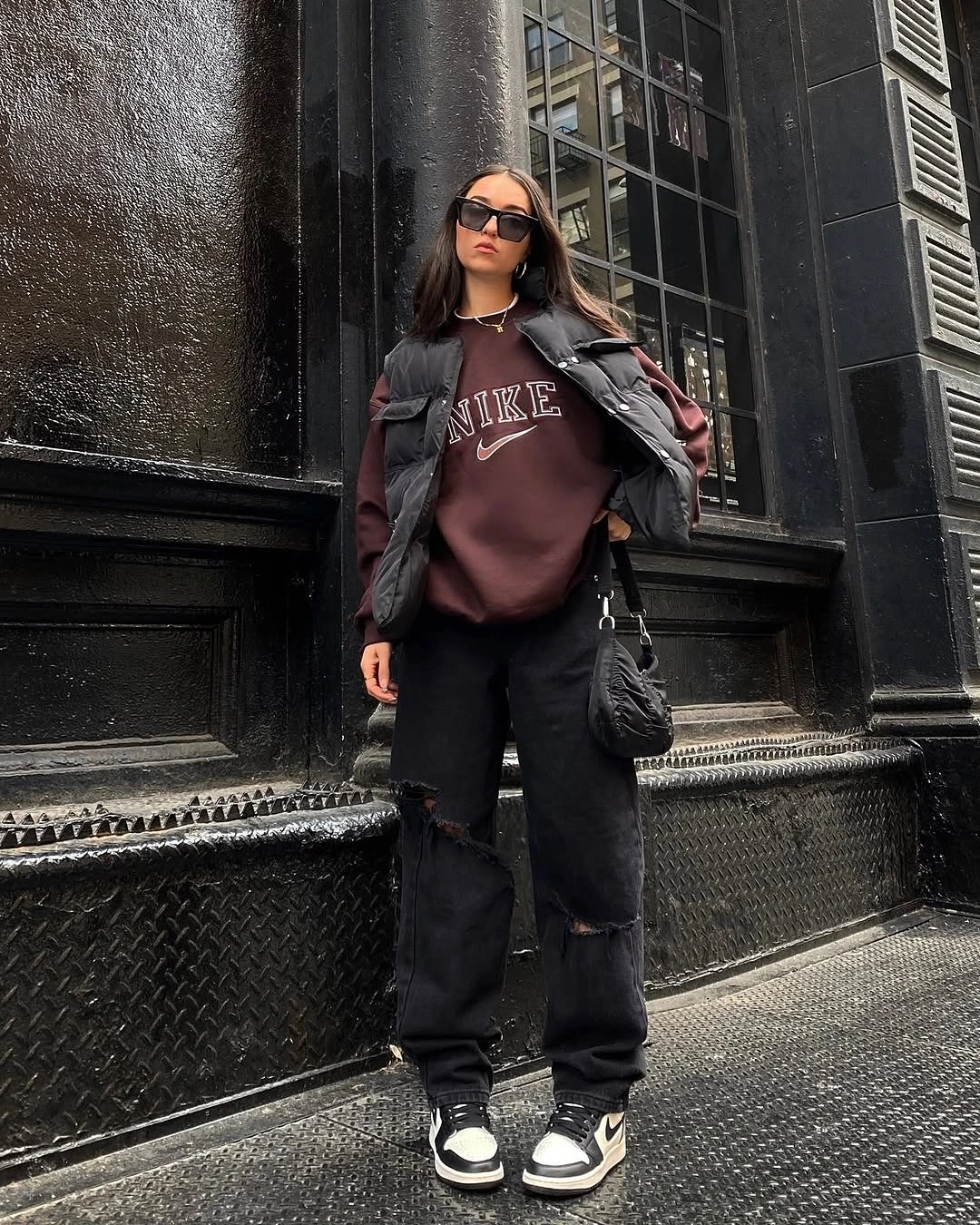 Burgundy sweatshirt under black puffer with dark pants and sneakers
