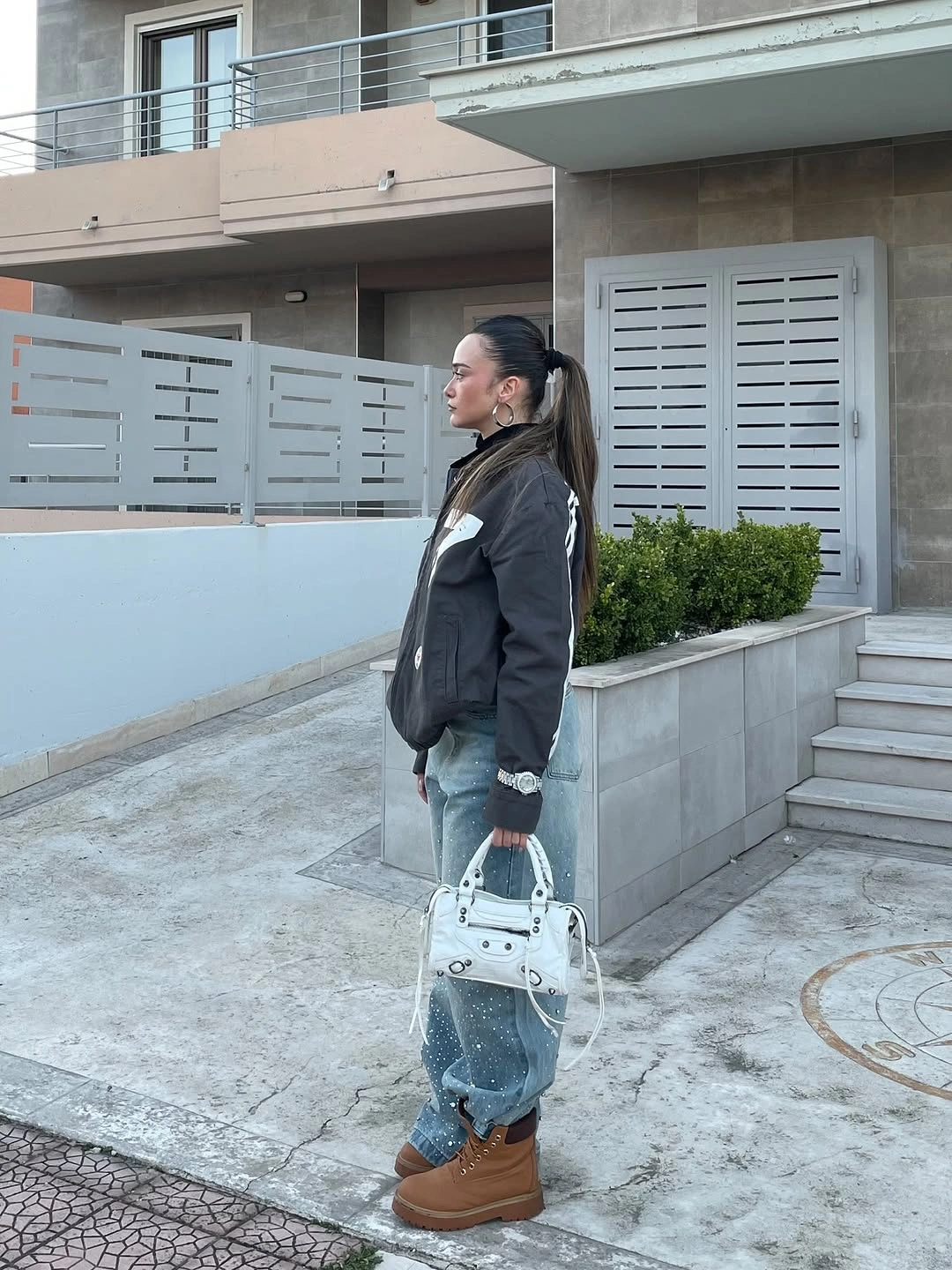 Short black jacket with light wide jeans, white bag, and platform boots