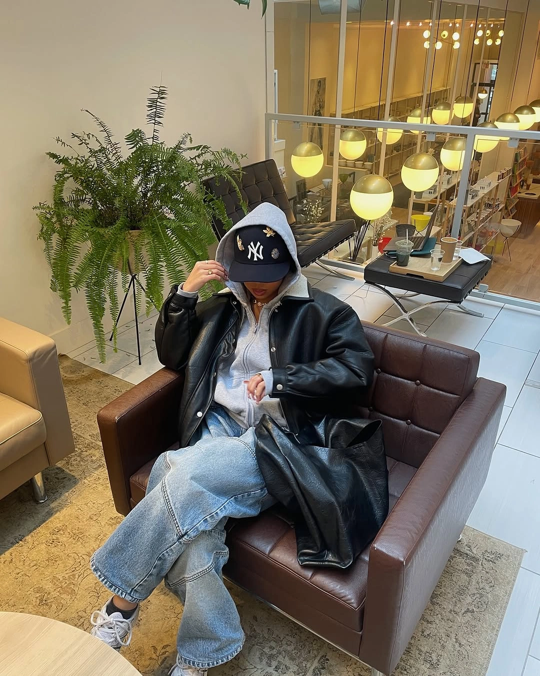 Long black coat with pale wide jeans, cap, and light sneakers